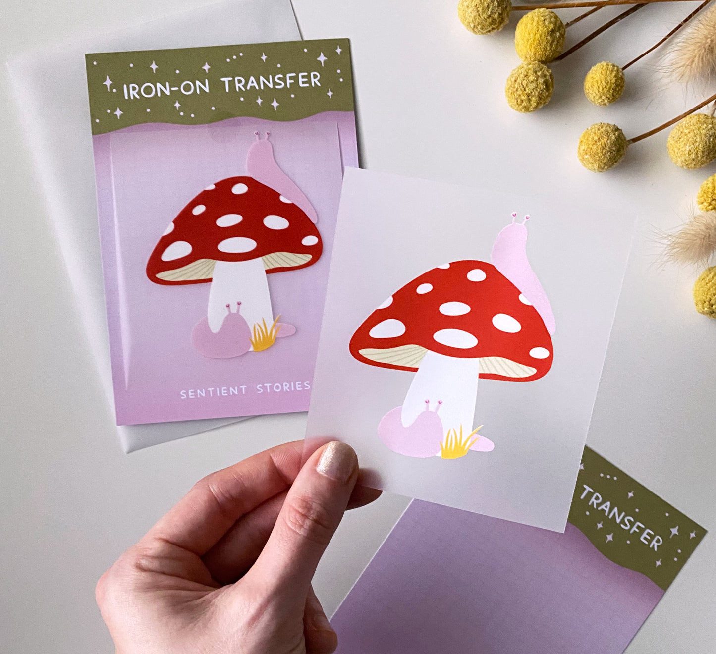 Iron-on transfer with mushroom design held by a hand on a white background