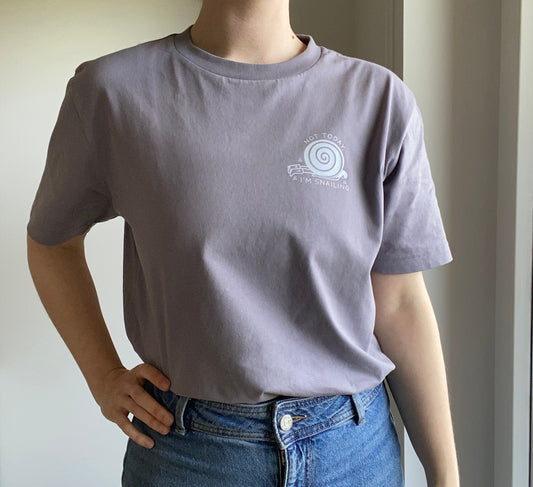 Person wearing an organic cotton gray t-shirt with a snail logo, standing against a neutral background